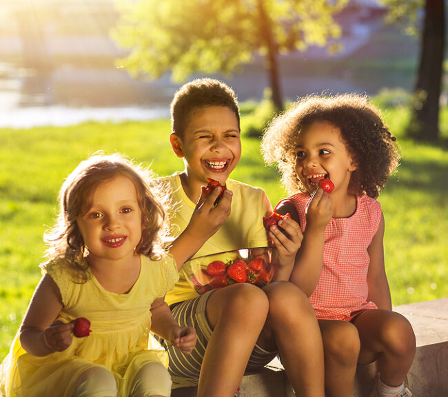 3 children enjoying fruit on a summer afternoon