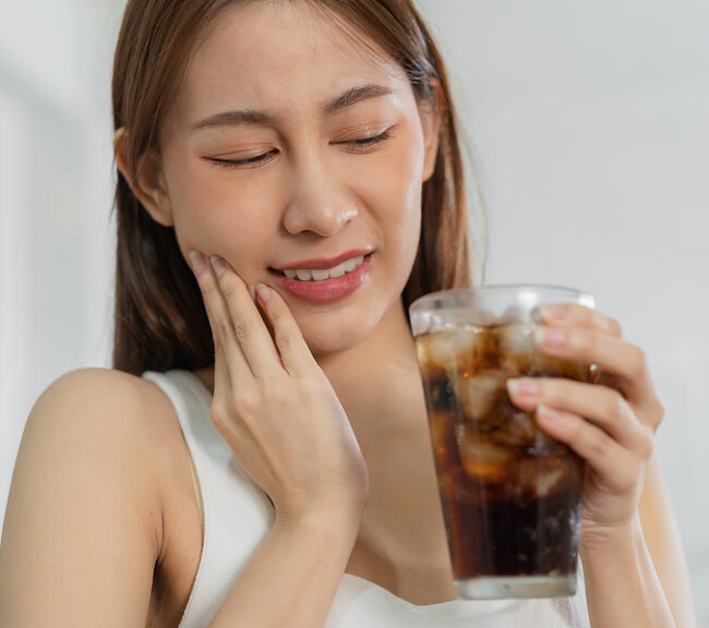 Healthy Asian lady holding a sugary drink. Sensitive teeth and in pain
