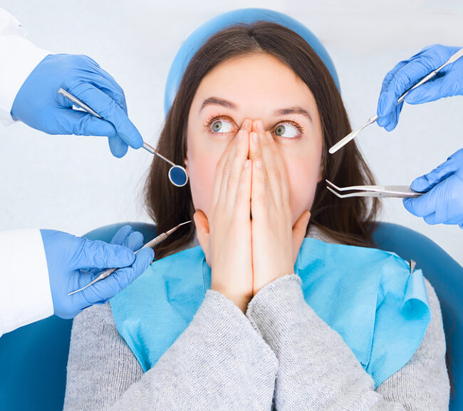 Save Download Preview Closeup doctor hands in gloves are holding dental instruments in clinic, office. Scared woman is closing her mouth with hands, preventing examining of teeth, because of fear. Visiting dentist concept.